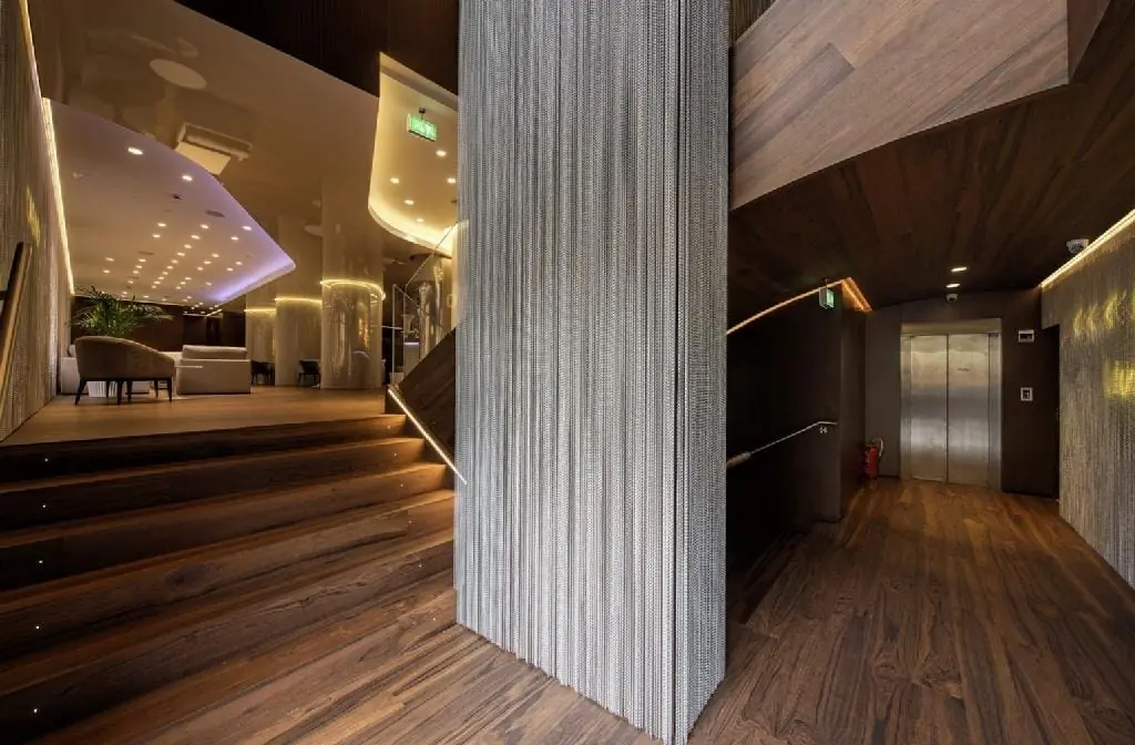 Escalera y revestimientos de madera en el Hotel Rincón de Pepe, Murcia, con barandilla de vidrio y suelo de nogal